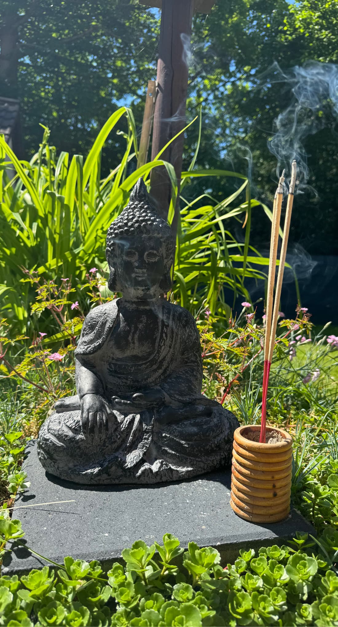 Buddha-Figur mit brennenden Räucherstäbchen im Garten des Massagestudios in Radolfzell-Böhringen